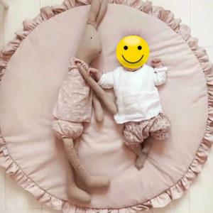 Bébé allongé sur un tapis rose de chambre pour bébé rond et doux