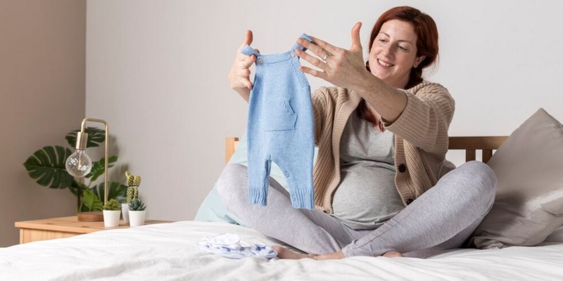 Femme enceinte avec vêtements pour bébé